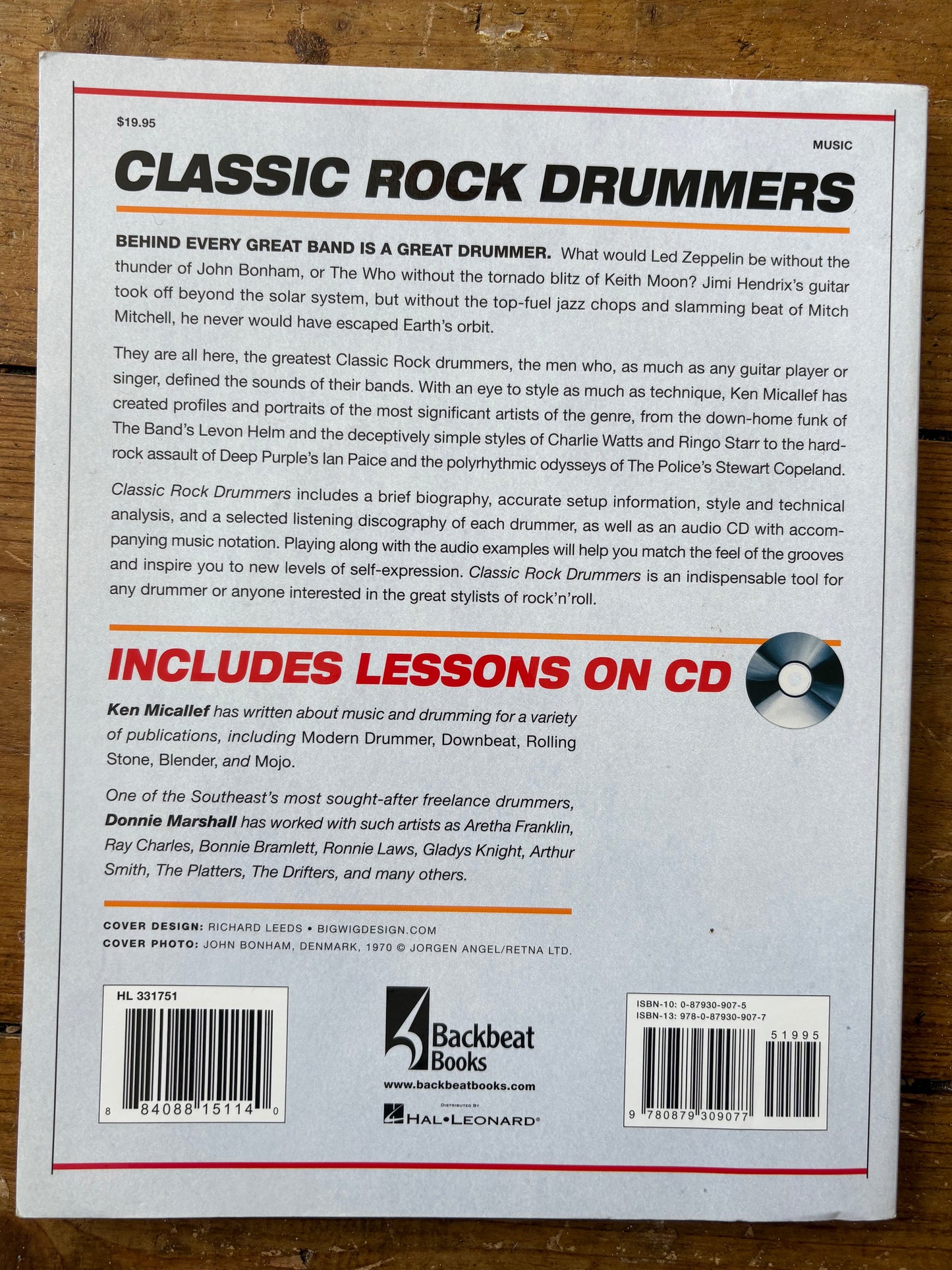 Back cover of a book titled 'Classic Rock Drummers' with text and a barcode on a wooden surface.